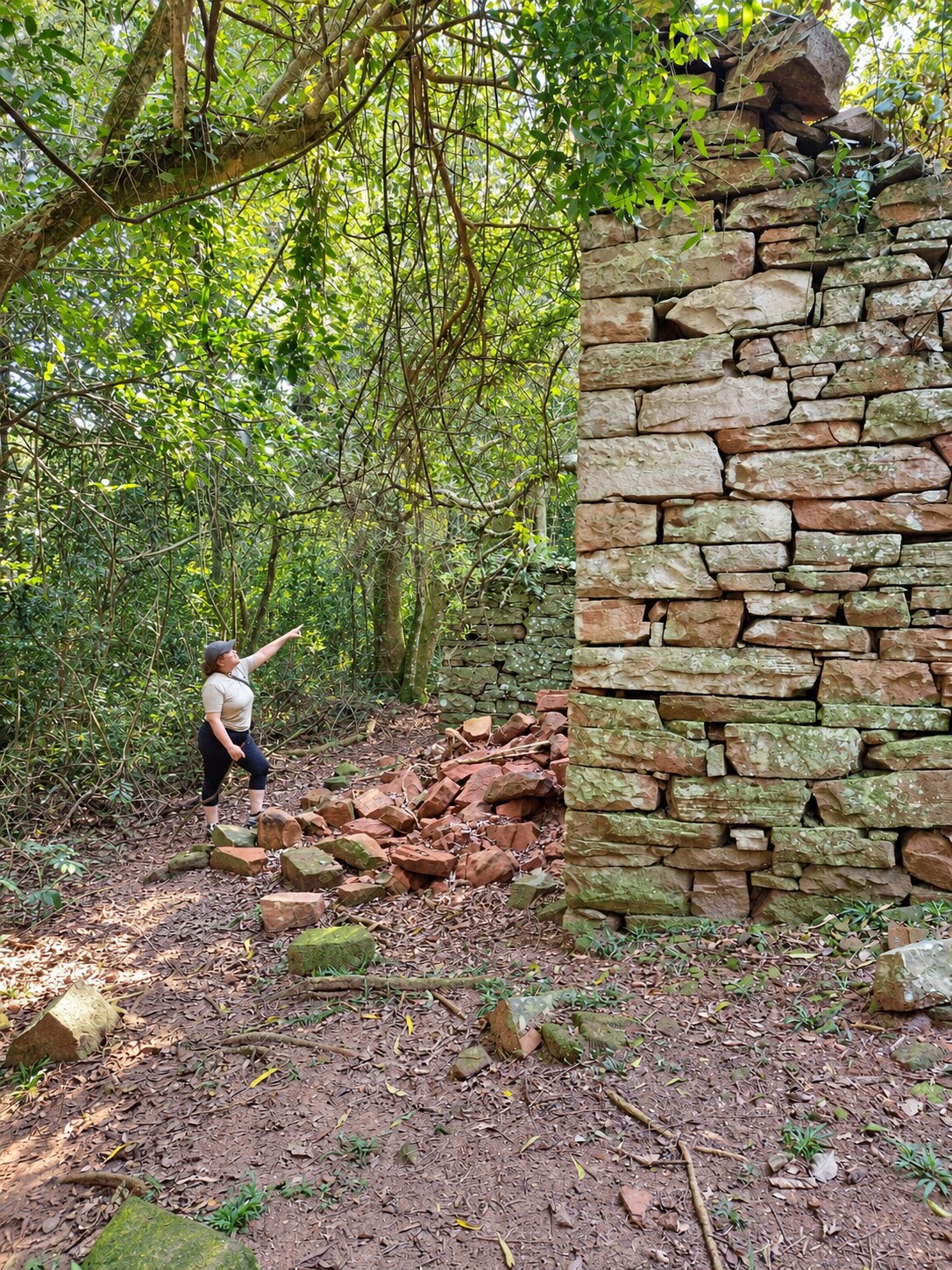 Visitante observando la antigua construcción de piedra dentro del monte